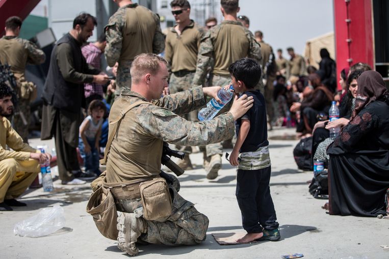 Een Amerikaanse militair deelt water uit aan Afghaanse burgers. Beeld REUTERS