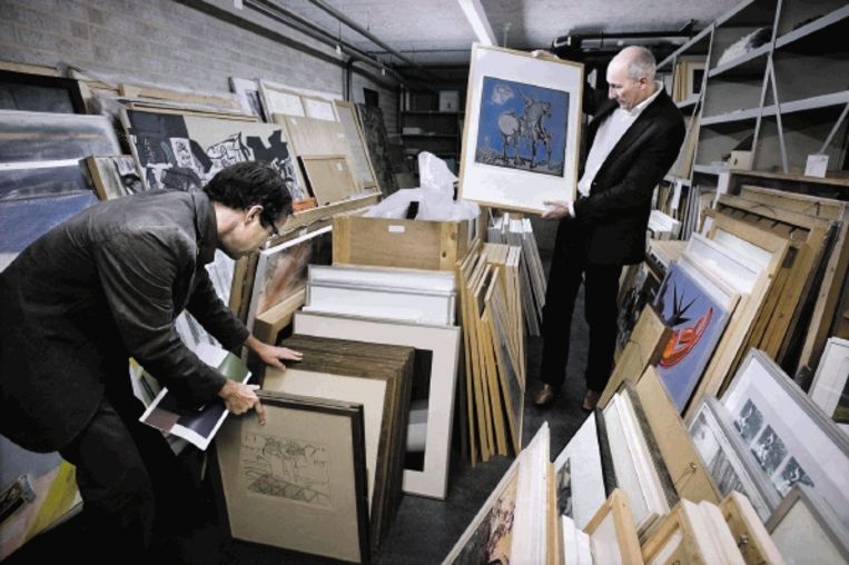 Wethouder Henk Beerten (rechts) grasduint door de gemeentelijke kunstcollectie die nu nog ruim 3000 stuks telt. (FOTO KOEN VERHEIJDEN) Beeld 
