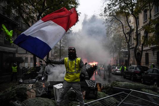 Een ‘geel hesje’ zwaait met de Franse vlag tijdens rellen in Parijs.