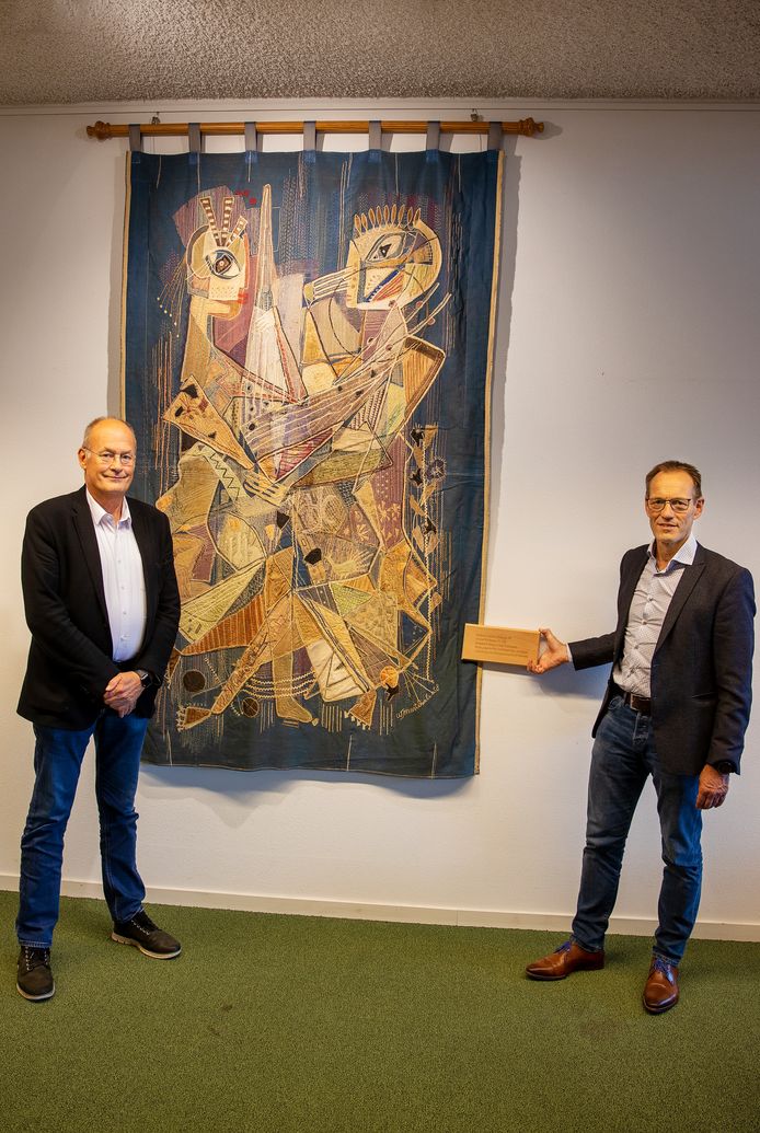 Hofnar-directeur Paul L'Herminez (links) en rector Edward de Gier van Scholengemeenschap Were Di bij het wandtapijt van Willi Martinali, dat sinds deze week in De Hofnar in Valkenswaard hangt.