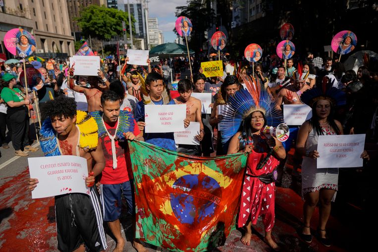 Activist Sonia Guajajara (tweede van rechts) en andere vooral inheemse Brazilianen. De vlag van het land is besmeurd met rode verf, een verwijzing naar het bloedvergieten tijdens een betoging tegen geweld, illegale houtkap, mijnbouw en veeteelt.  Beeld AP