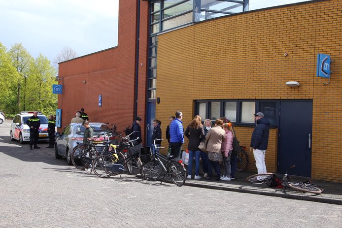 Commotie na het incident aan de achterzijde van supermarkt Albert Heijn. Rechts de beschadigde fiets, links de auto van de man.