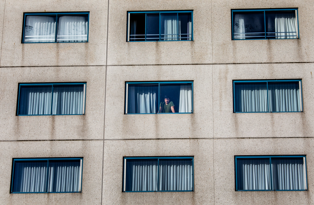 Een bewoner van het quarantainehotel kijkt uit het raam. Beeld Raymond Rutting / de Volkskrant
