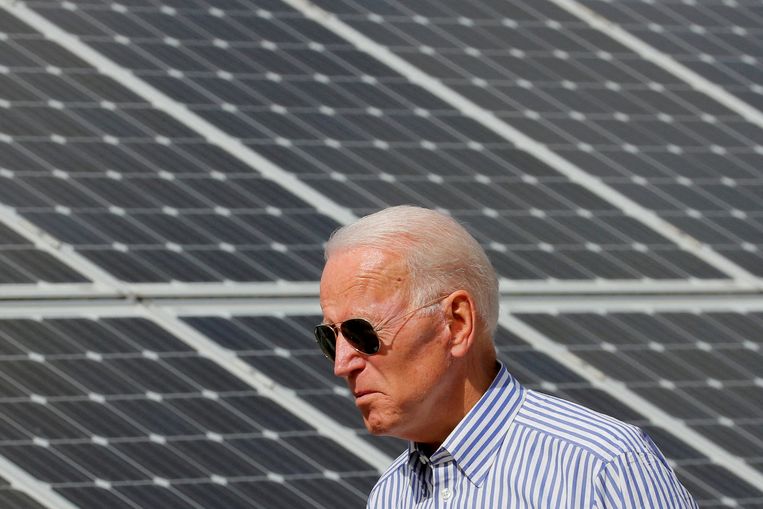 Joe Biden loopt dinsdag langs een veld zonnepanelen in de staat New Hampshire, als onderdeel van een reeks bezoeken aan infrastructuurprojecten.  Beeld REUTERS