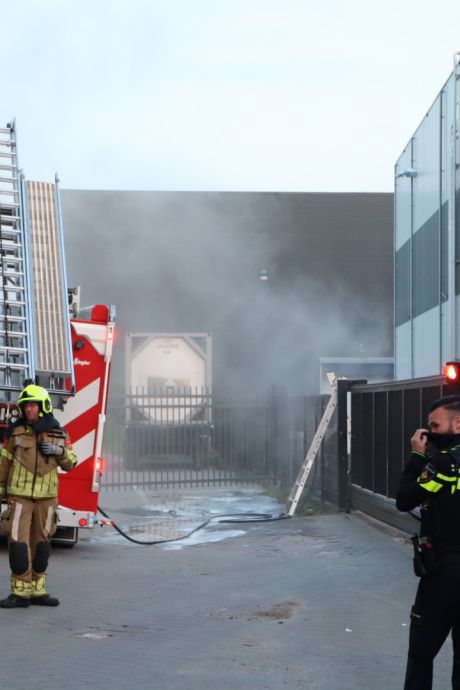 Zak met chemisch afval vliegt in brand bij bedrijf in Waspik, brandweerlieden klimmen over hek