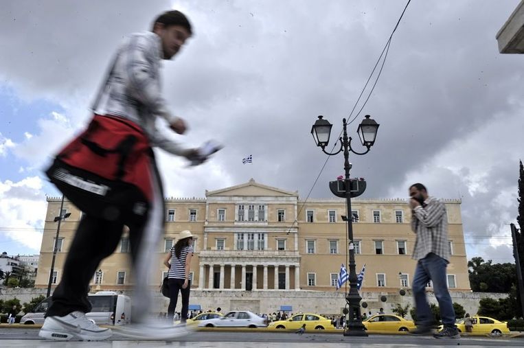 Grieken lopen voorbij het Grieks parlement in Athene Beeld afp