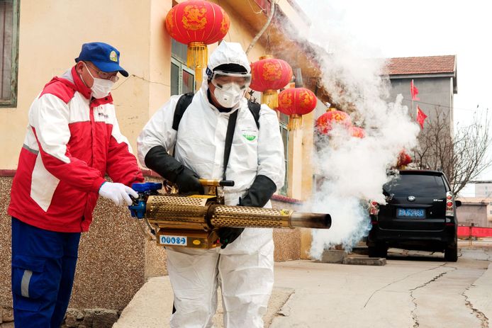 Een man in beschermende kledij desinfecteert een straat in China in aanloop naar de nieuwjaarsfeesten.