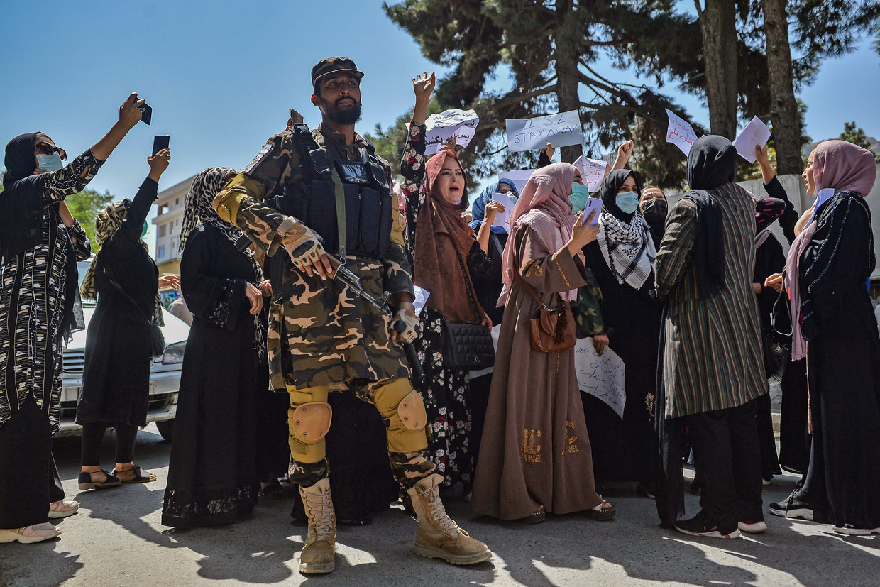 Vrouwen protesteren in Kaboel, een Talibanstrijder houdt de wacht.  Beeld AFP