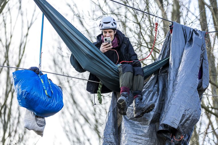 Hoog tussen de bomen van het Sterrebos in Born hangt de hangmat van deze activist. Hij probeert een uitbreiding van autofabriek VDL Nedcar tegen te houden. Beeld ANP