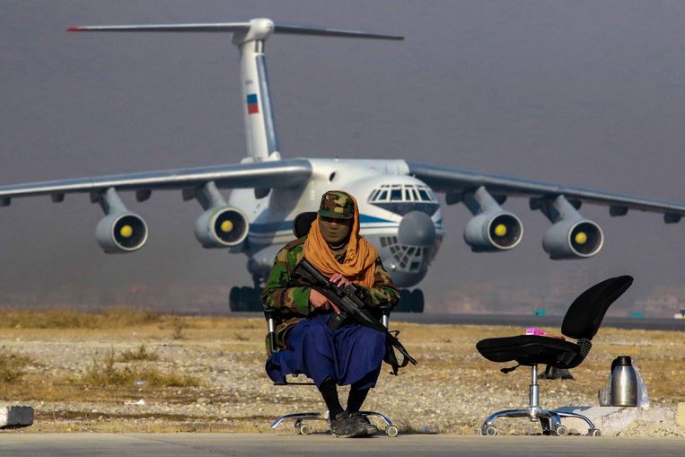Een Talibanstrijder houdt de wacht bij een transportvliegtuig op het vliegveld van Kaboel. Beeld EPA