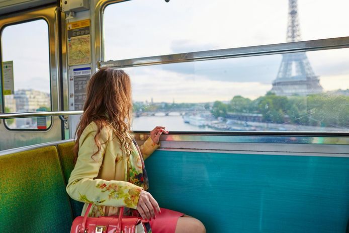 Beautiful young woman travelling in a train of Parisian underground and looking through the window at the Eiffel tower