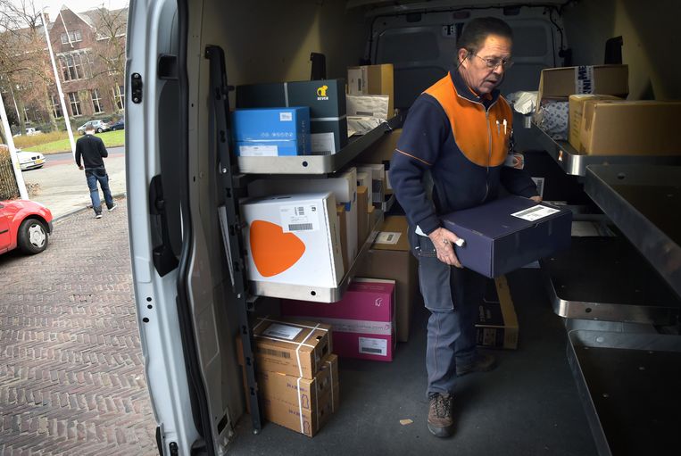 Een pakketbezorger van PostNL zoekt naar het juiste postpakket. Beeld Marcel van den Bergh