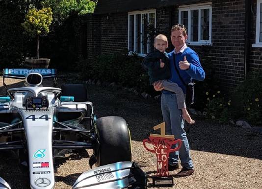 Harry Shaw en vader James voor hun huis naast de F1-bolide van Mercedes.