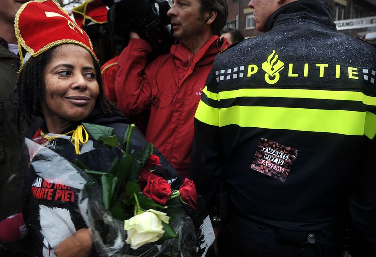Iemand heeft een sticker tegen Zwarte Piet op de rug van een agent geplakt. Beeld Marcel van den Bergh/de Volkskrant