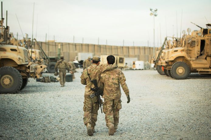 Foto van december 2014. Een Amerikaanse soldaat loopt weg met een arm geslagen om een Afghaanse tolk.