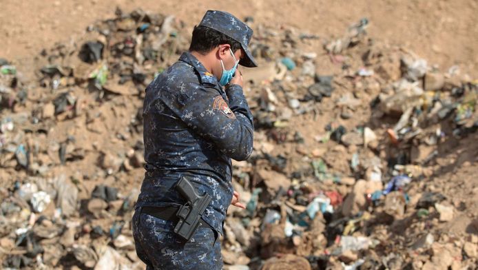 Een lid van de Iraakse regeringstroepen ruimt een zojuist ontdekt massagraf