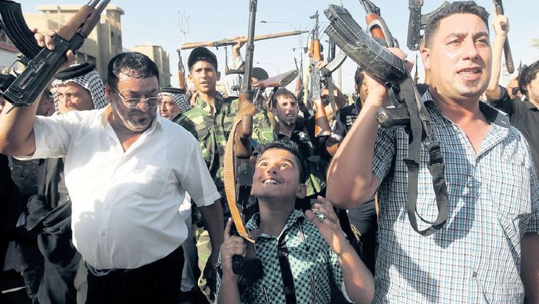 Een Iraakse jongen houdt zijn wapen omhoog tussen burgers die zich hebben aangemeld bij het Iraakse leger om te vechten tegen Isis. Beeld afp