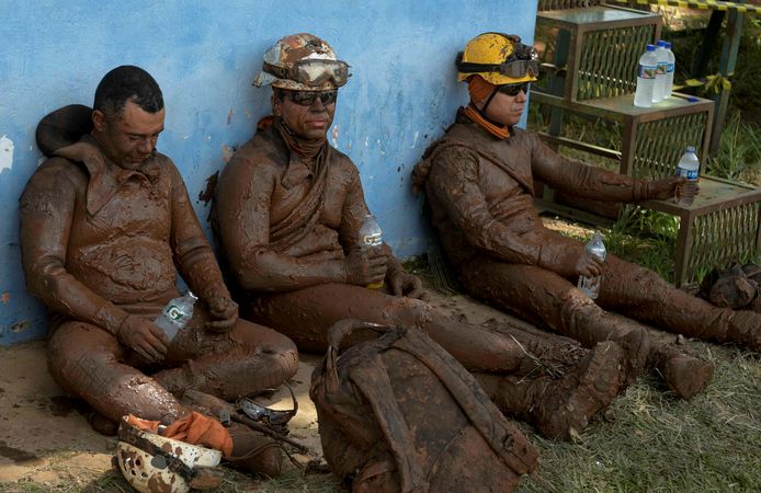 Reddingswerkers die helemaal onder de modder zitten houden even pauze.