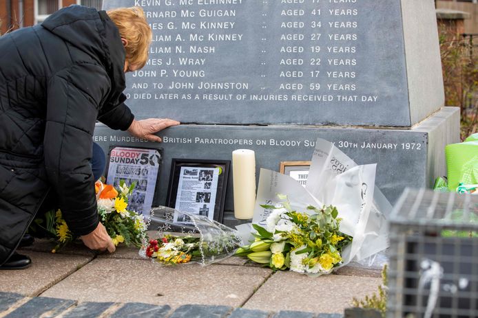 Een vrouw legt bloemen neer bij een herdenkingsmonument in Bogside, Derry.