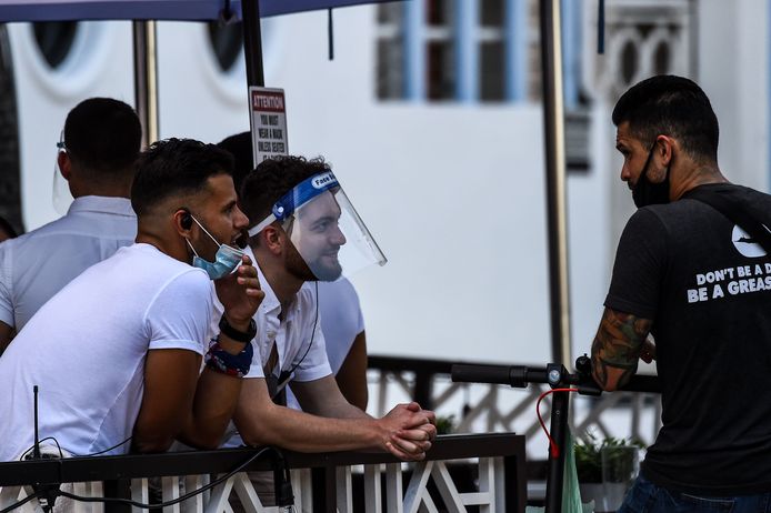 Mensen met een mondkapje en een gezichtsscherm wachten op hun bestelling in Florida.