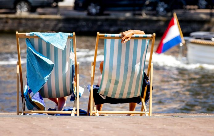 Mensen liggen in een strandstoel bij de Kattensloot in Amsterdam op een bloedhete dag in juli tijdens de eerste hittegolf in drie jaar tijd.