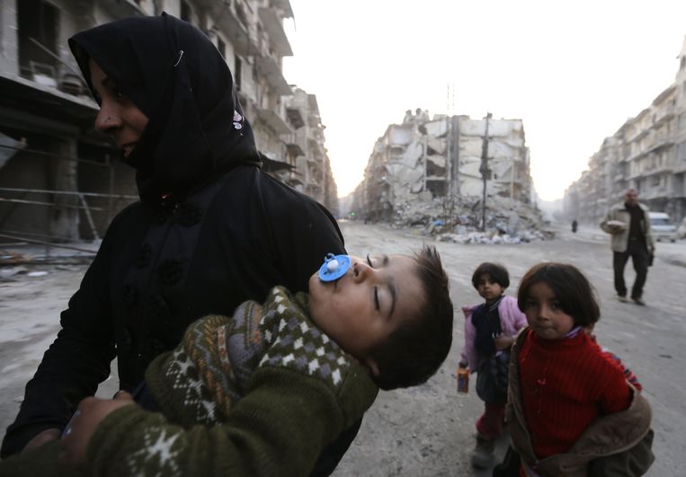 Een Syrische vrouw draagt een van haar kinderen op de arm in Aleppo.  Beeld AFP