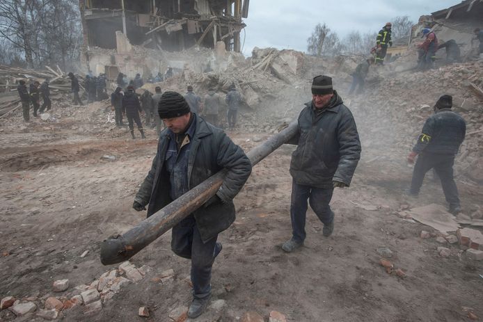 Mensen verwijderen puin bij een Oekraïense militaire basis in Okhtyrka die door Rusland werd gebombardeerd. (08/03/2022)