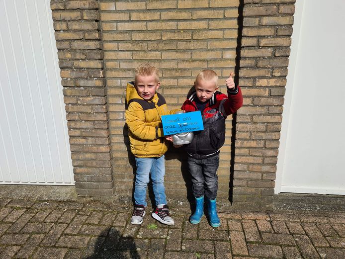 'Geef ons onze speeltuin terug en doneer!' staat op een briefje dat hier omhoog wordt gehouden door Jay Deijkers (l) en Joris Tol.