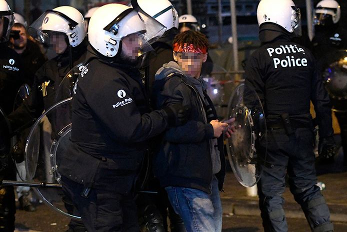 Een jongere wordt opgepakt door de politie na de rellen aan het Muntplein in Brussel.