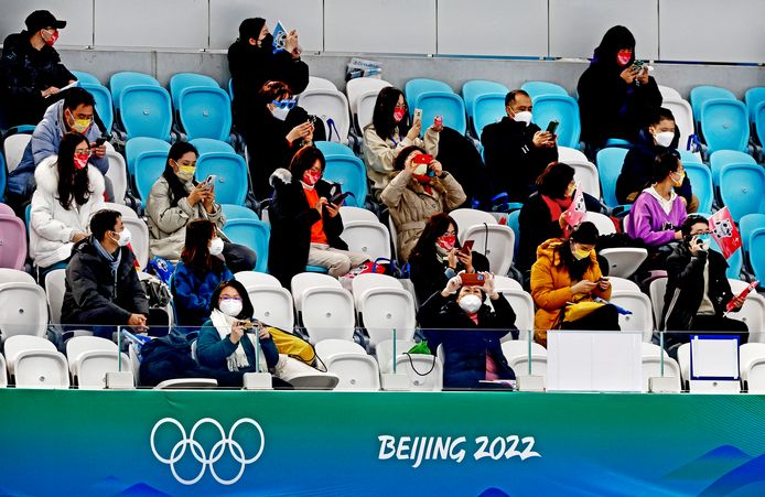 Het schaatspubliek heeft vooral oog voor hun telefoontje.