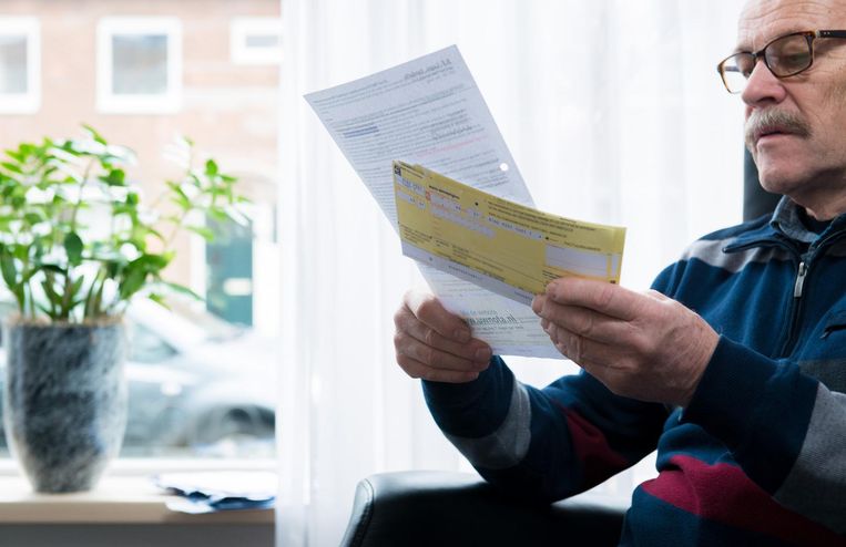 Een gepensioneerde automonteur neemt een stapeltje rekeningen door. Beeld ANP