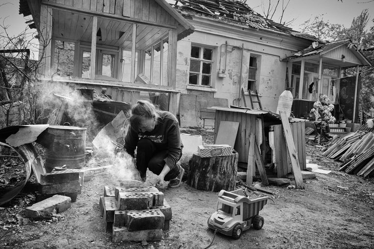 In de tuin van haar tijdens een bombardement verwoeste huis in Irpin maakt Oksana Doednik tussen bakstenen met kleine takjes een vuurtje aan, waar ze de koffiekan opzet. Ze woont er met haar twee kleinkinderen van 11 en 9. Beeld Eddy van Wessel