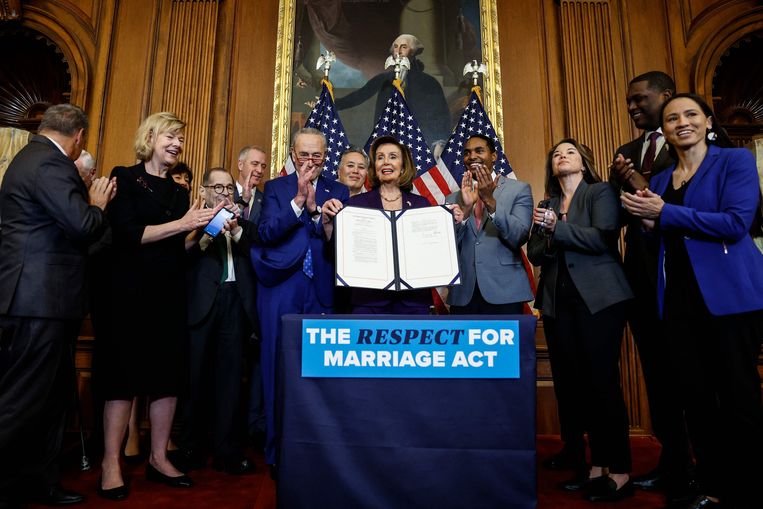 Nancy Pelosi, de Democratische voorzitter van het Huis van Afgevaardigden, toont samen met een groep politici van beide partijen de nieuwe wet.  Beeld Getty Images via AFP