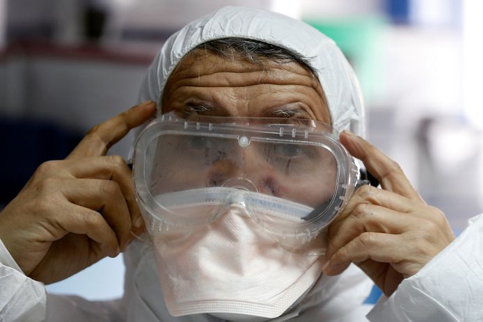 Een lid van de medische staf van een ziekenhuis in Amman laat zien hoe de artsen zich beschermen bij de behandeling van een patiënt die mogelijk is besmet met het coronavirus.