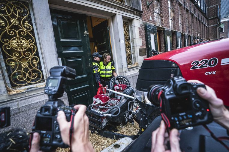 Politieagenten, ondergespoten met stro, staan in de deuropening van het provinciehuis in Groningen. Iets later worden de deuren open gereden met een trekker.  Beeld ANP