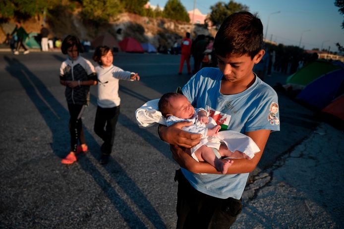 Een jongen houdt zijn pasgeboren broertje in de armen. De kinderen brachten de afgelopen nachten door op straat op Lesbos.