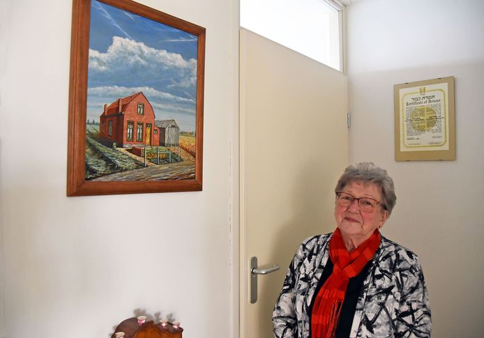 Adrie van Overdulve-de Kraker in de hal van haar appartement in Terneuzen. Links het schilderij van haar ouderlijk huis in de Lovenpolder bij Hoek. Achter haar hangt het certificaat van de Israëlische Yad Vashem-onderscheiding die in 1994 postuum aan haar ouders werd toegekend.