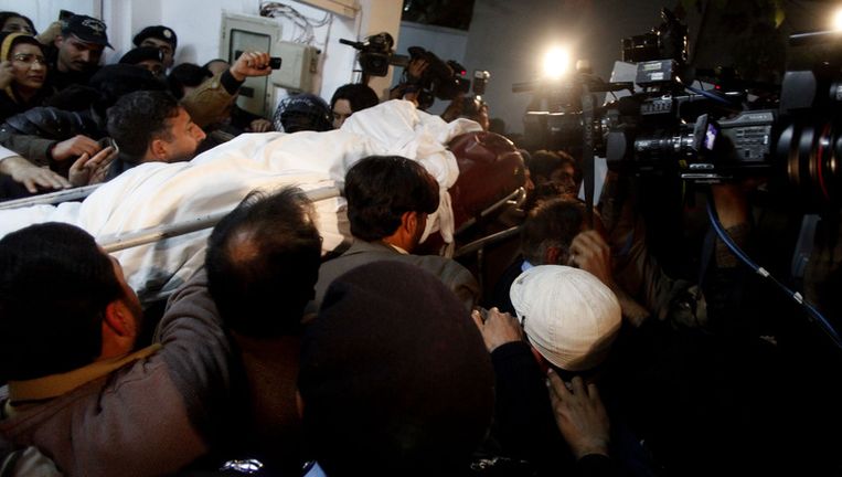 Omstanders dragen het lichaam van de vermoorde gouverneur naar een ambulance. Beeld ap