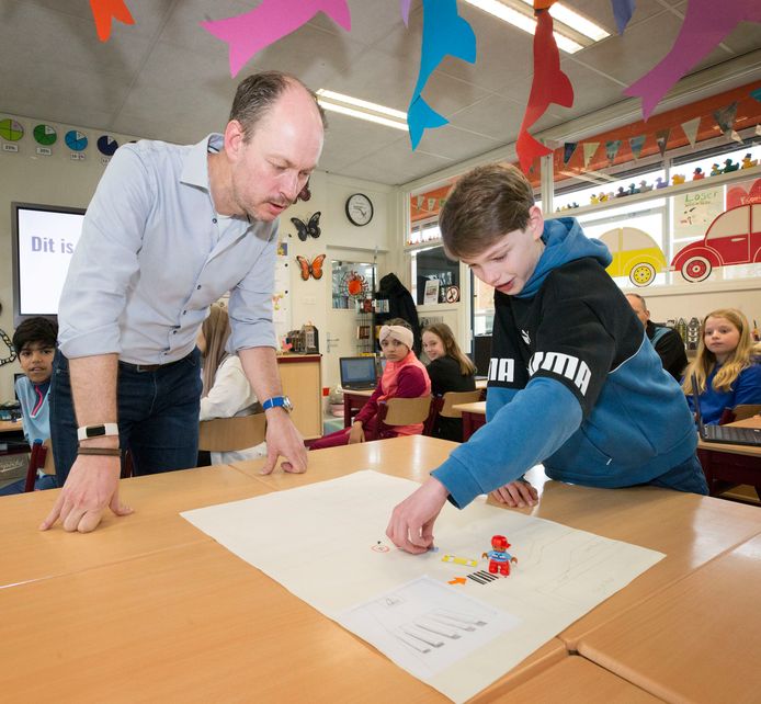 Een leerling van groep 8 van basisschool De Burchtgaarde in Breda geeft uitleg aan wethouder Daan Quaars bij de zelfgemaakte plattegrond van de verkeerssituatie in de Rijnauwenstraat.