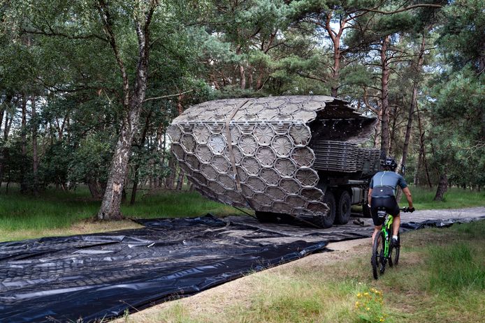 Een militair voertuig rolt een weg van stalen matten uit voor de opvanglocatie van Afghaanse evacuees in Heumensoord, waar ook een populaire mountainbikeroute loopt.