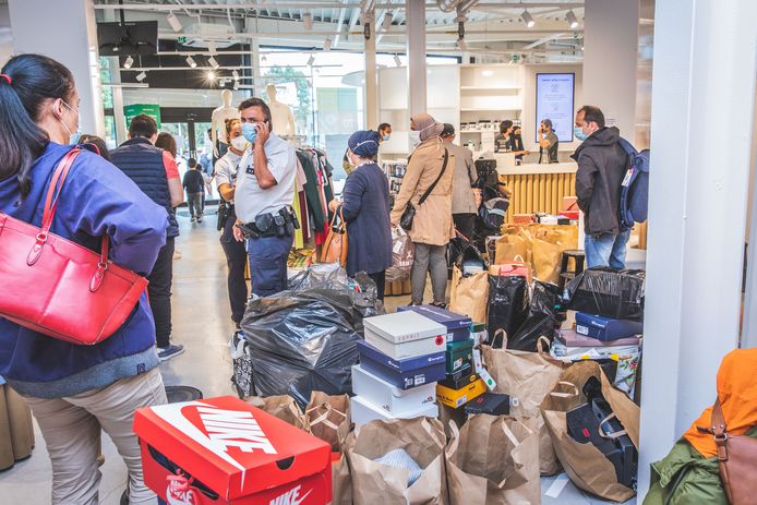 Brantano Gentbrugge. Mensen schuiven aan met zakken vol schoenen. De politie maant in de winkel aan dat maar één persoon per bubbel in de winkel blijft om aan te schuiven en betaling te doen.