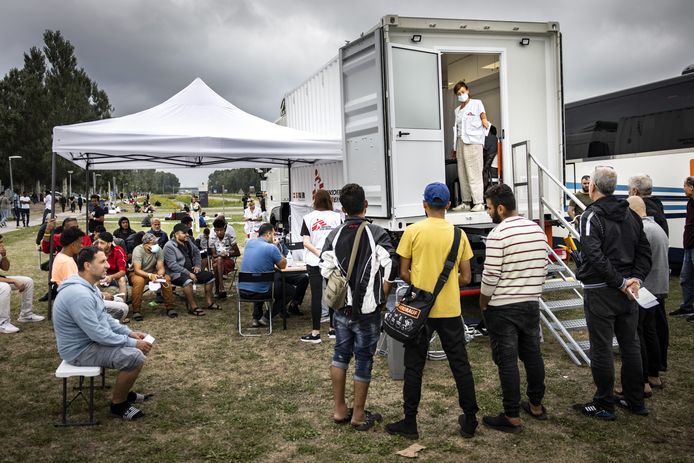 Foto ter illustratie. Asielzoekers staan buiten de poort van het aanmeldcentrum in Ter Apel.