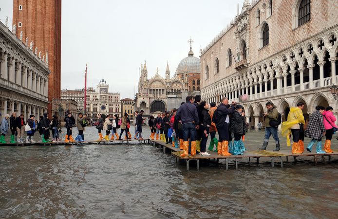 Met provisorische bruggetjes en plastic zakken om de schoenen proberen de toeristen de voeten droog te houden aan het Dogepaleis.