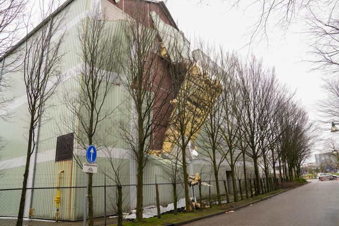 Metalen platen van het bedrijfspand van textielfabriek Raymakers bungelen aan de zijkant van het pund.