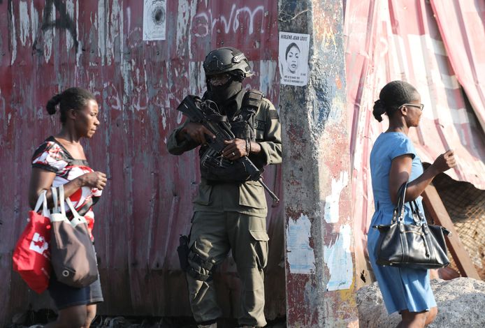 Vrouwen lopen langs een zwaarbewapende militair in de Haïtiaanse hoofdstad Port-au-Prince.