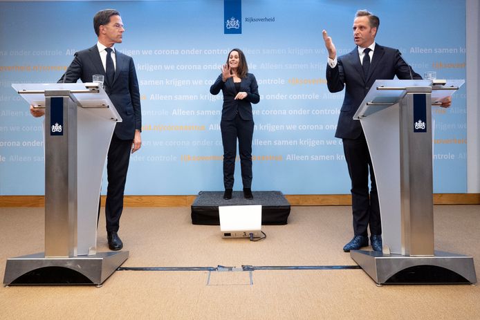 De coronapersconferentie 'oude stijl': premier Mark Rutte en minister Hugo de Jonge met in hun midden de gebarentolk. Aan een nieuwe opzet wordt nu gesleuteld.