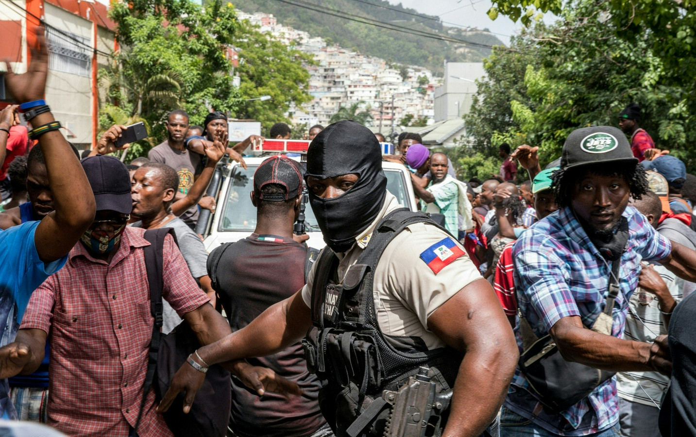 Des policiers et des personnes dans la rue à Haïti au commissariat de police où sont détenus les suspects de l'assassinat du président.