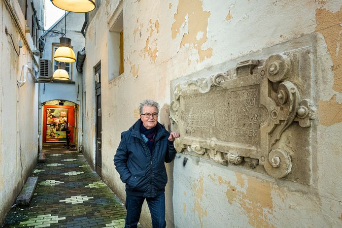 Theo Brink bij de Zutphense gevelsteen van de Walburgiskerk. Ingemetseld in een smal steegje aan de Weverstraat in Arnhem.
