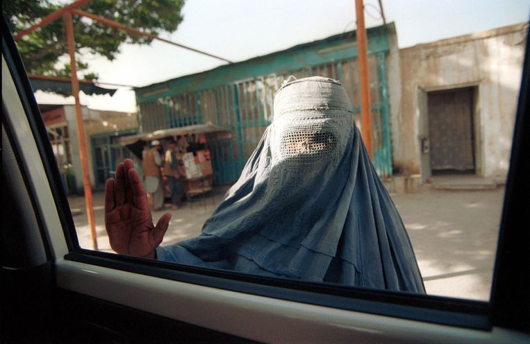 Een vrouw in boerka legt haar hand op het raam van een wagen. Beeld © Lynsey Addario / 2021 The Atlantic Monthly Group, Inc.   All rights reserved. Distributed by Tribune Content Agency