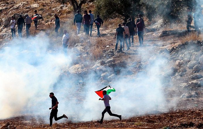Palestijnse demonstranten rennen weg van de traangasbommen.
